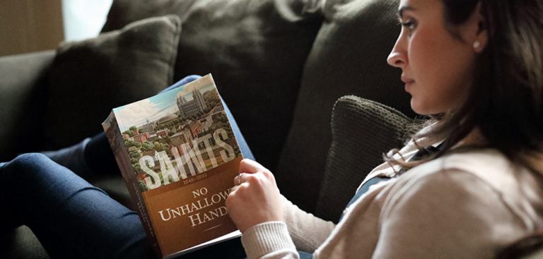 A woman holding a copy of the book: "Saints"