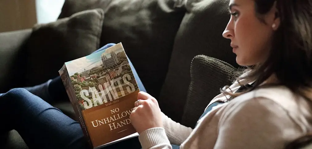 A woman holding a copy of the book: "Saints"