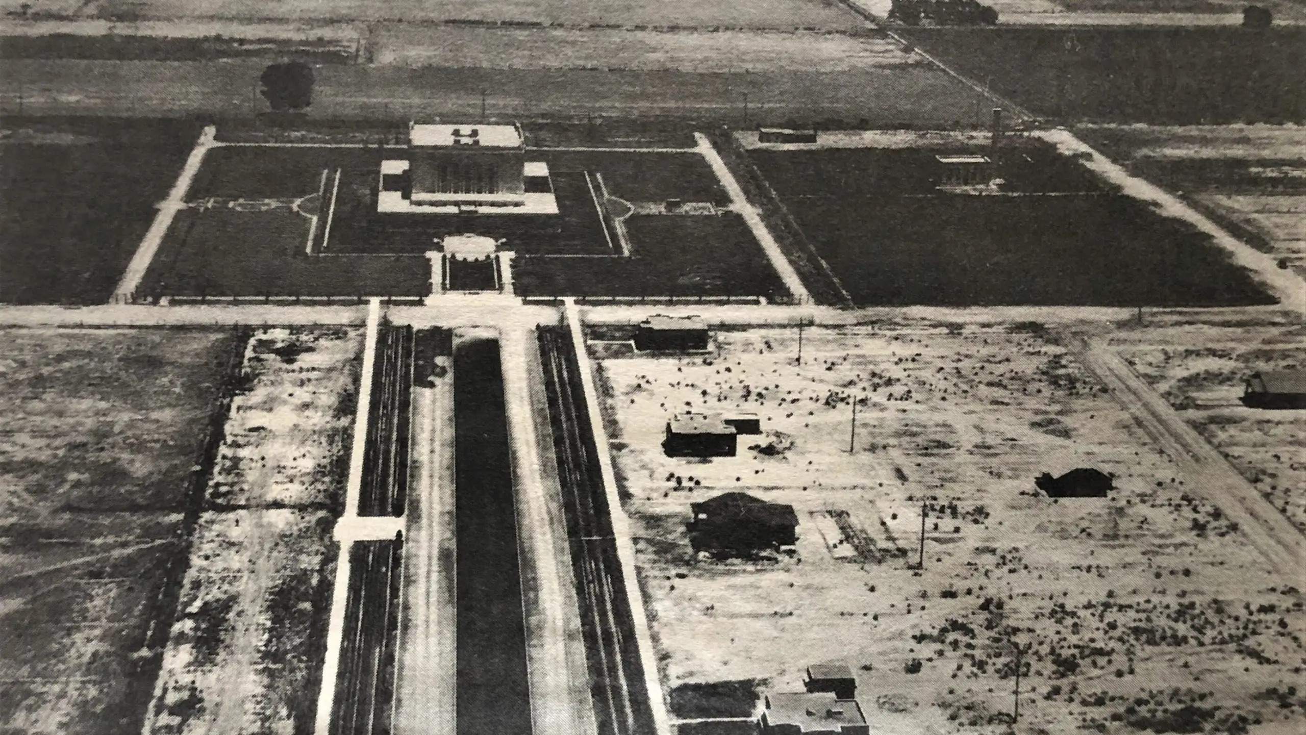 這張亞利桑那州梅薩聖殿的照片拍攝於 1928 年。很明顯，這座聖殿確實位於鄉村。當時，梅薩鎮的人口只有 3,500 人，城鎮範圍僅延伸到東部的梅薩大道（Mesa Drive），也就是這張照片的前景。這張照片是沿著第一大道朝寺廟的西入口看的。第一大道中間的黑色地帶是犁過的行，每年種植罌粟。寺廟兩側的田野種植苜蓿和玉米。後來，北田種植了橘子樹和柚子樹，遊客中心於 1957 年建成，並於 1981 年改建，並於 2018 年拆除。照片由 ED Newcomer 提供，由 Nyle Leatham 提供。發表於《後期哨兵》，1981 年 2 月 27 日。