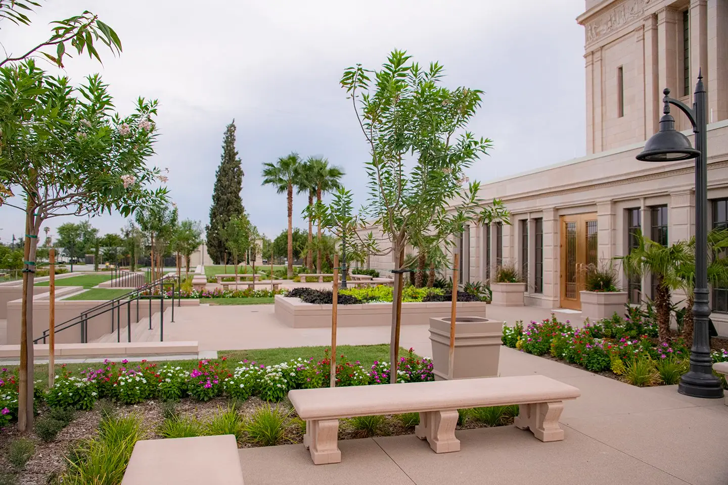 Trees and a stone bench outside the Mesa Temple beneath an overcast sky.